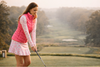 Female golfer getting ready to take a swing dressed in layered golf outerwear