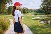 Female golfer walking on a path at the golf course wearing a navy skort