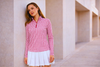 Woman leaning against wall wearing long sleeve golf shirt