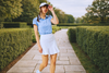 Woman wearing golf attire walking on a garden pathway