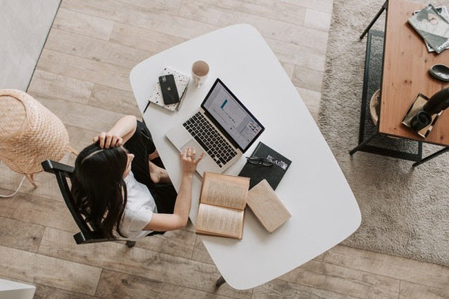 a woman working from home at a desk with a laptop